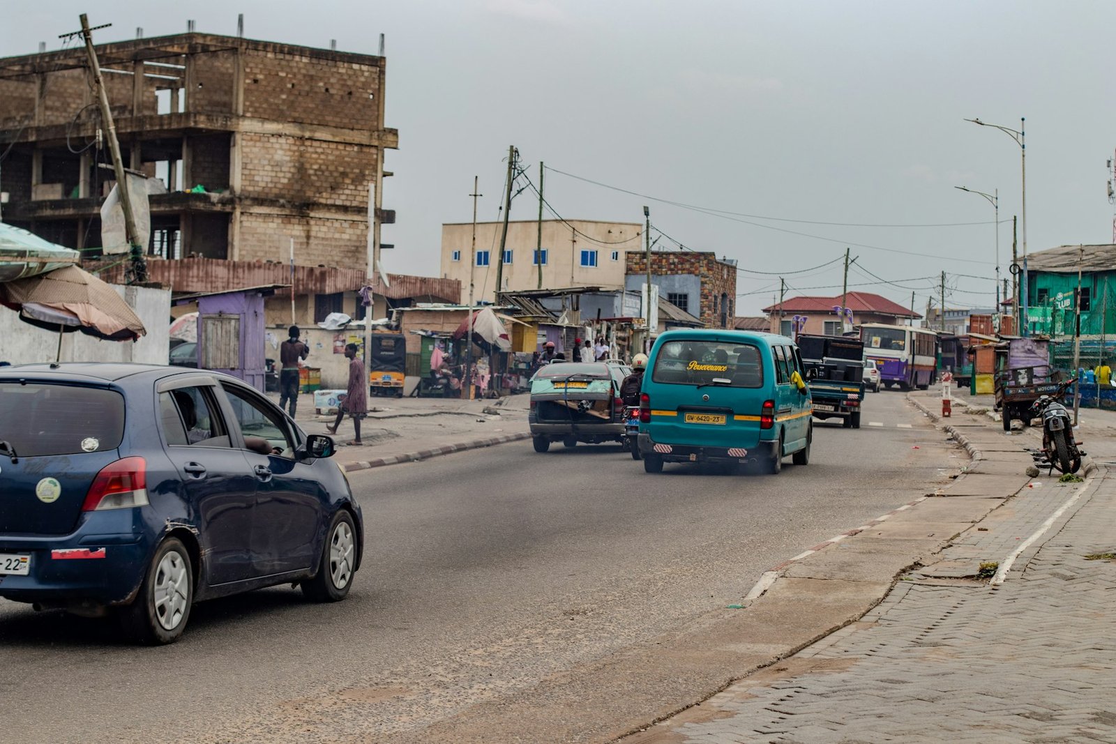 A busy African city street with cars, minibuses and people