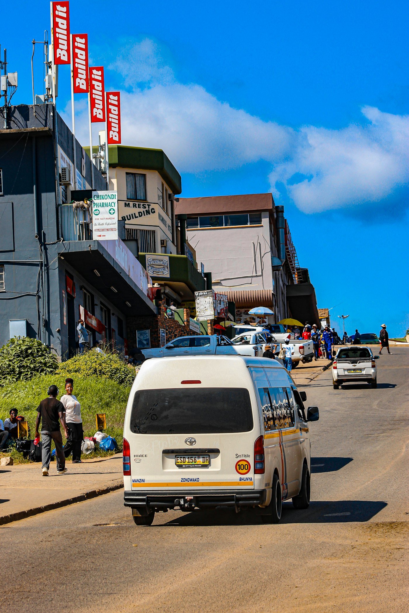 A minibus taxi driving up a sunny street